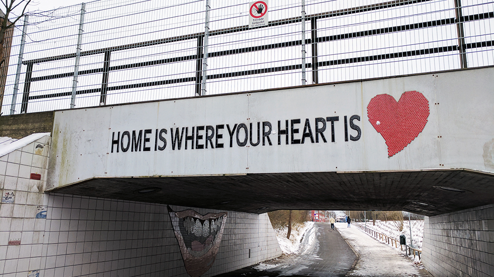 An underpass with the words "Home is where your heart is" is spray-painted. Picture