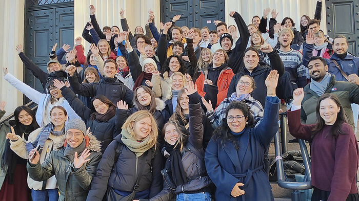 Students cheering on stairs outside university building