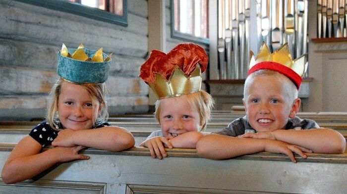 Illustrasjonsfoto av tre barn med kongekroner på kirkebenk